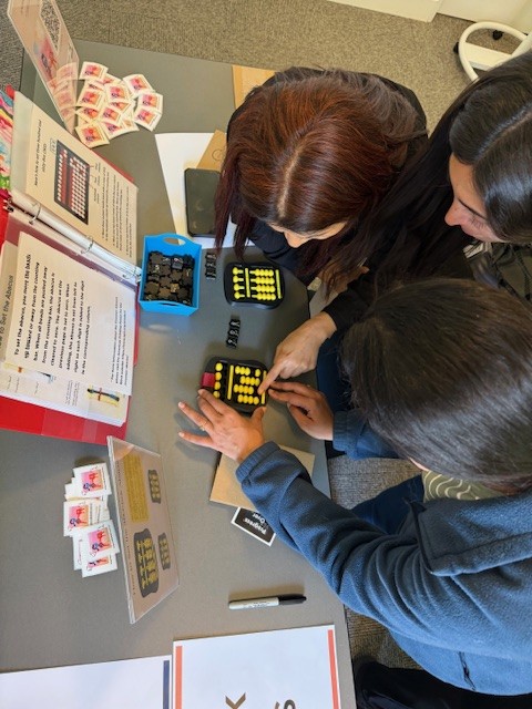 Three individuals using two 3D-Clicks at the activity table that has step by step instructions.