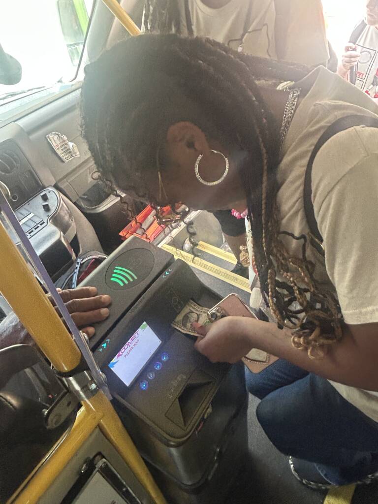 A female traveler pays the bus fare on a fixed route bus. 
