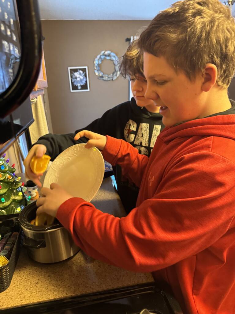Liam and his brother making a Christmas simmer pot in a small crock pot. 