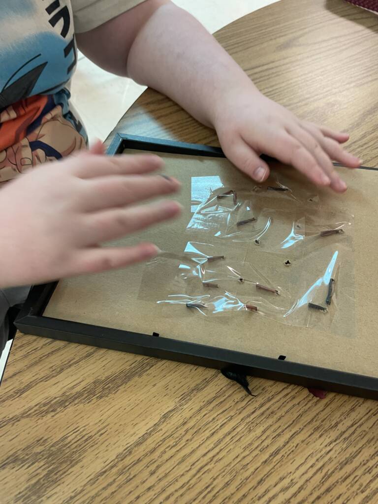 A student securing the back of the project with tape. 