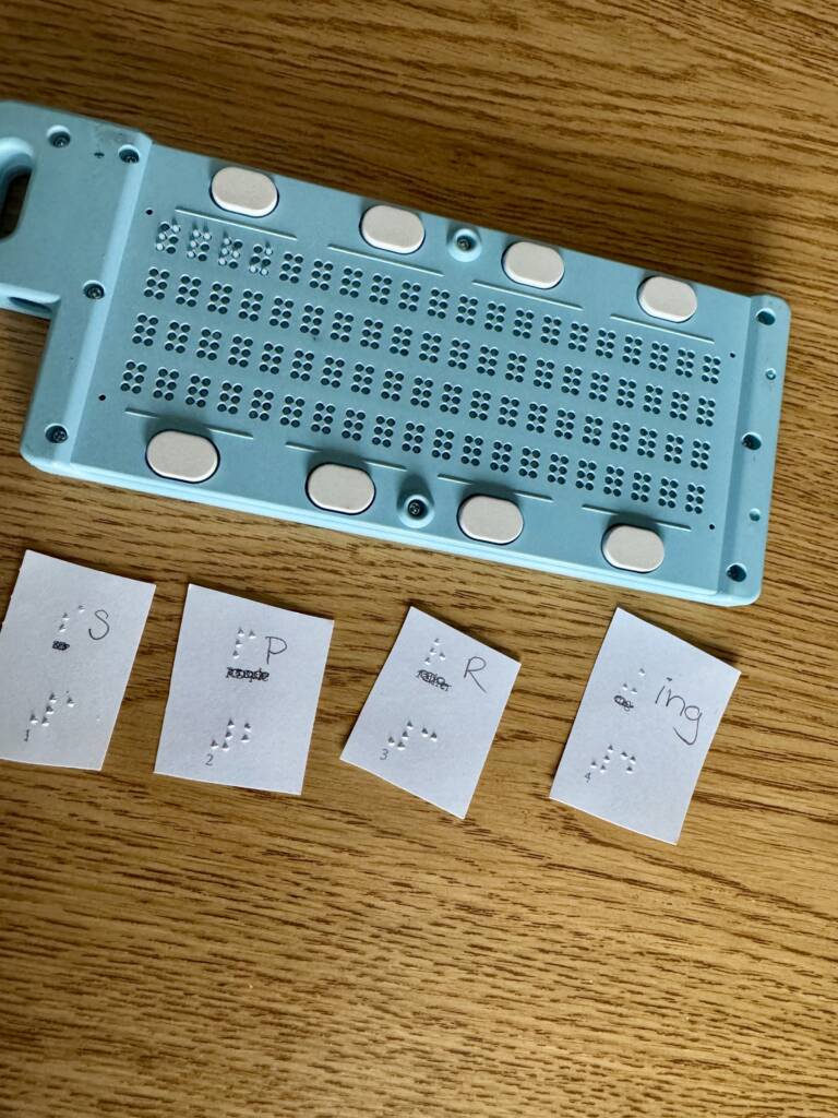 Slate and stylus with small braille cards that spell out SPRING