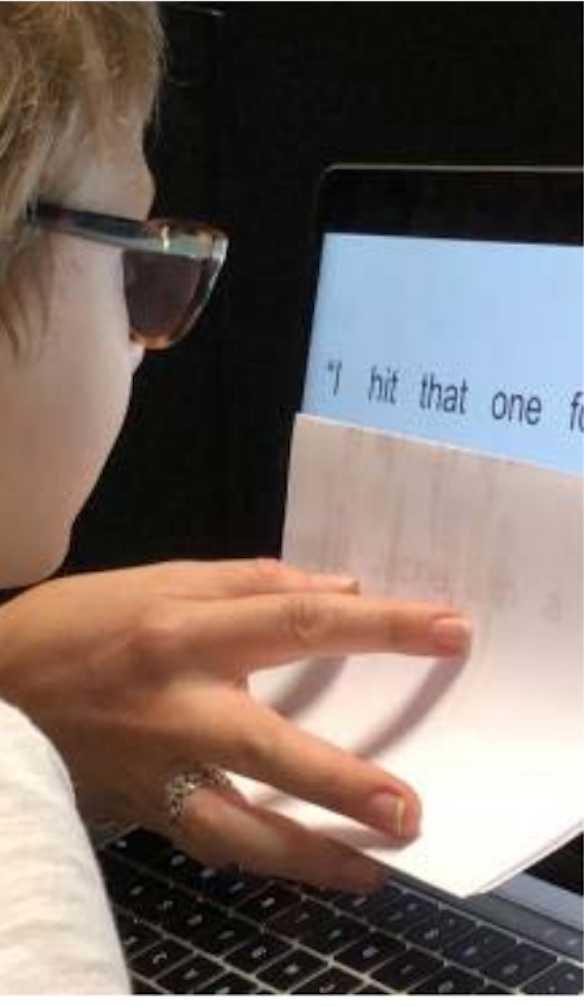 A boy uses a piece of paper to block out extra text on a computer screen