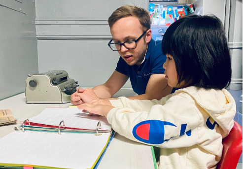 Jonathan working with a young Braille student