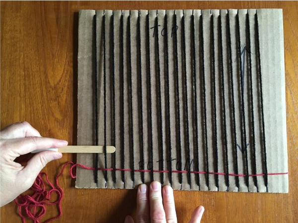 Putting your shed stick over the warp yarn Putting your shed stick over the warp yarn